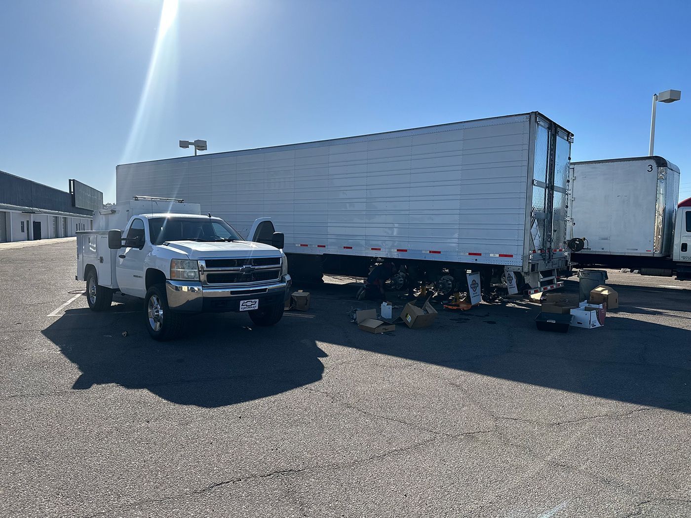 A white truck is parked next to a white trailer in a parking lot.