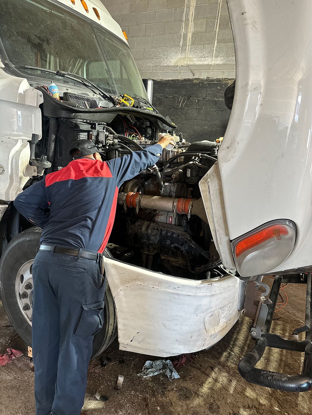 A man is working on the engine of a semi truck.