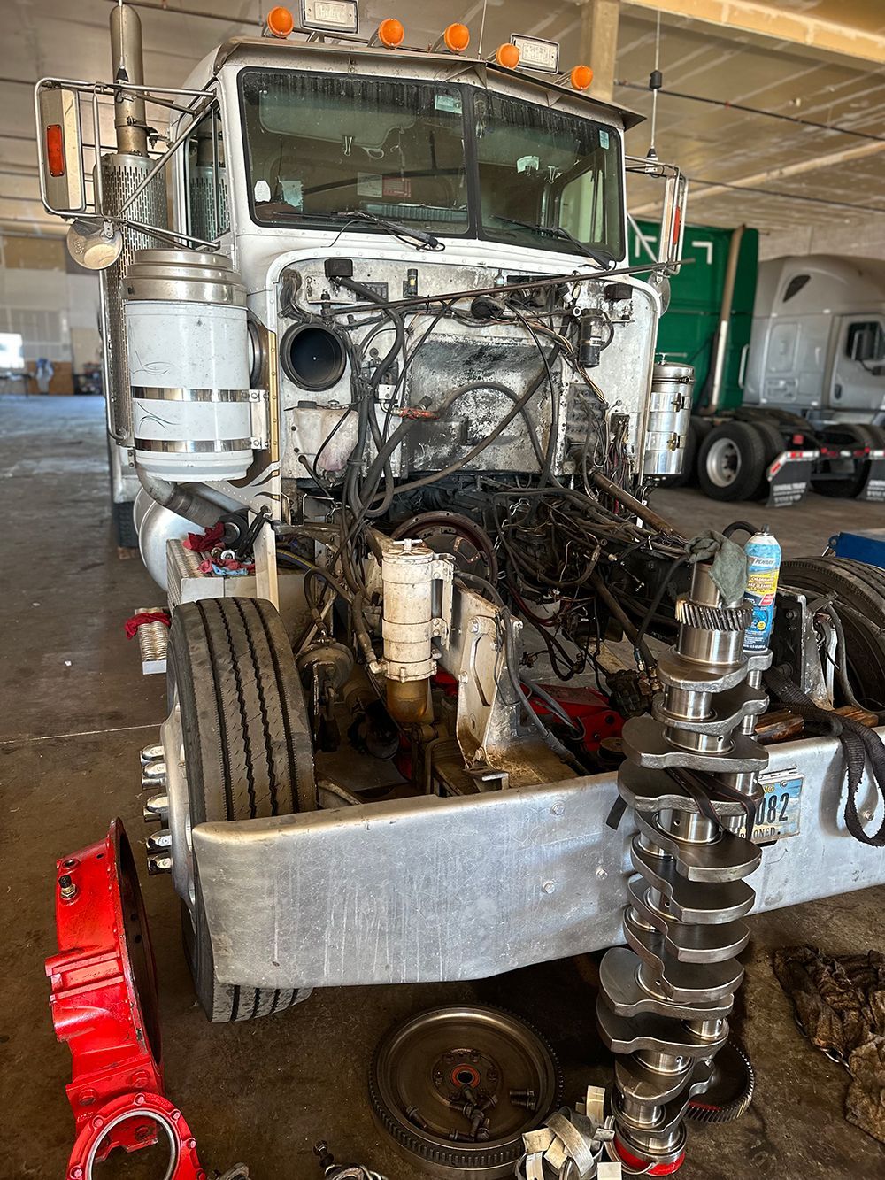 A semi truck is being repaired in a garage.