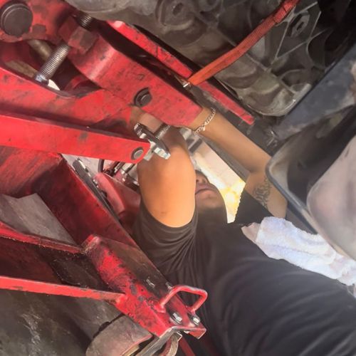 Person working on a car using a red lift.