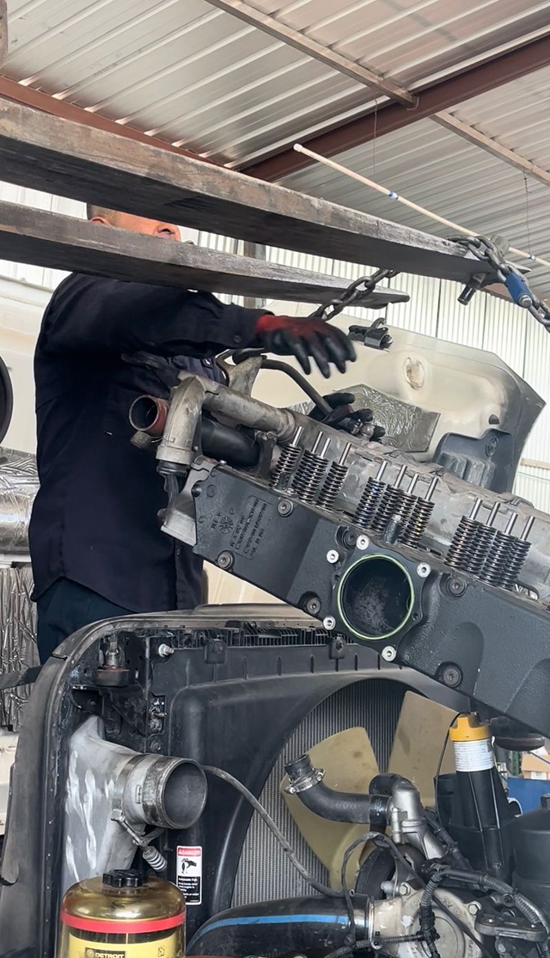 Mechanic working on truck engine in a garage; using tools.