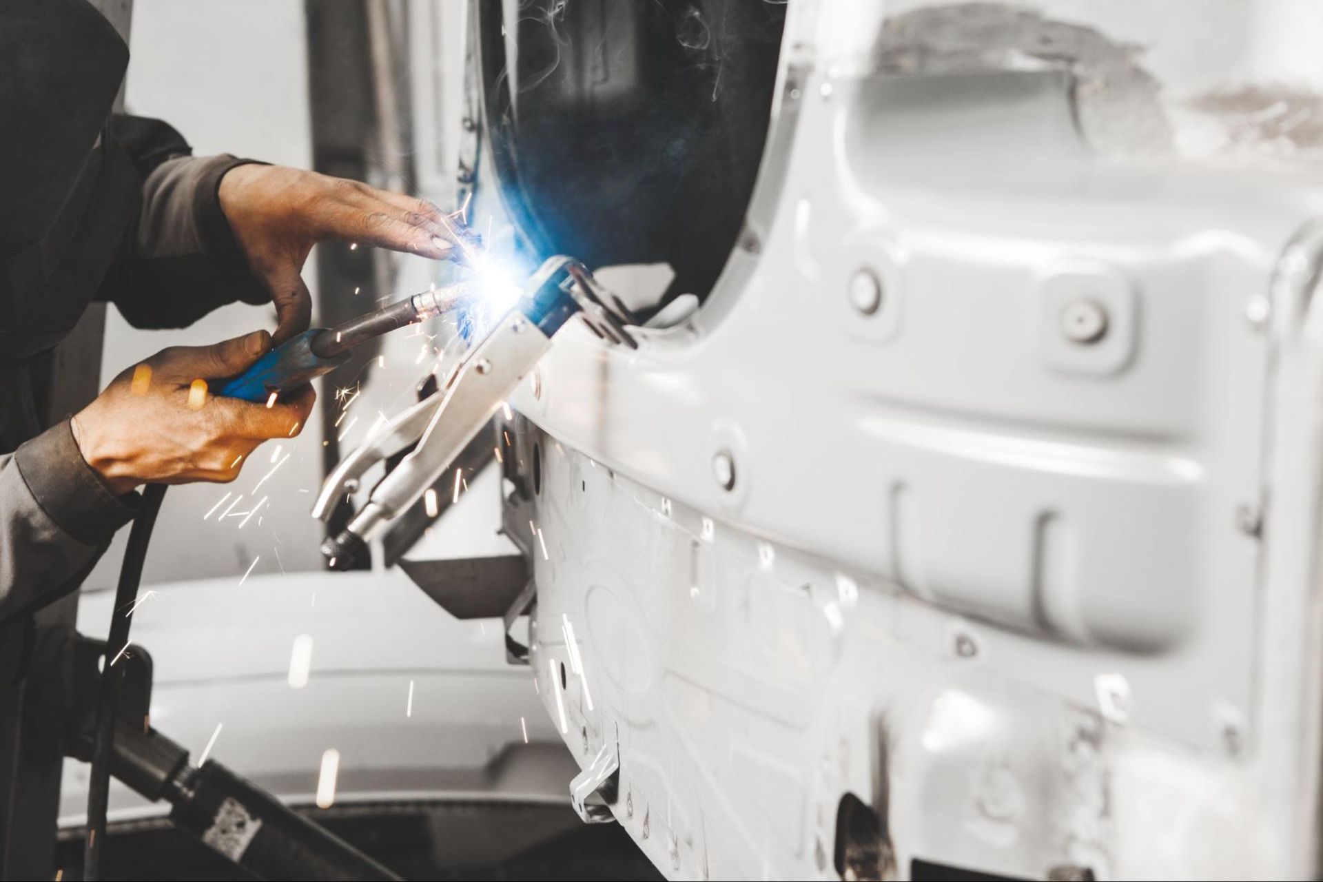 A man is welding a car in a garage.