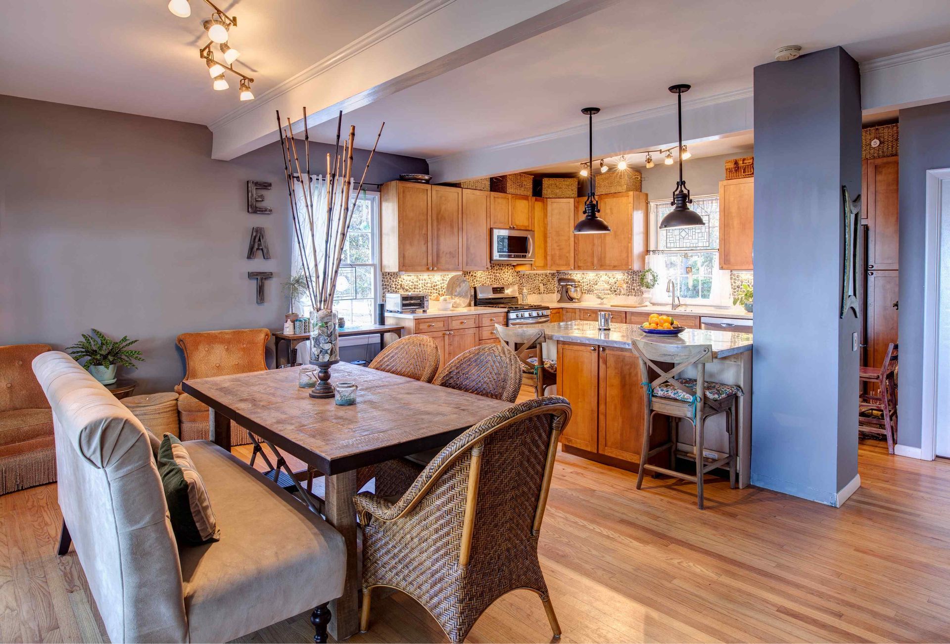 Open-concept dining and kitchen with wooden cabinets, a rustic dining table, and light wood flooring.