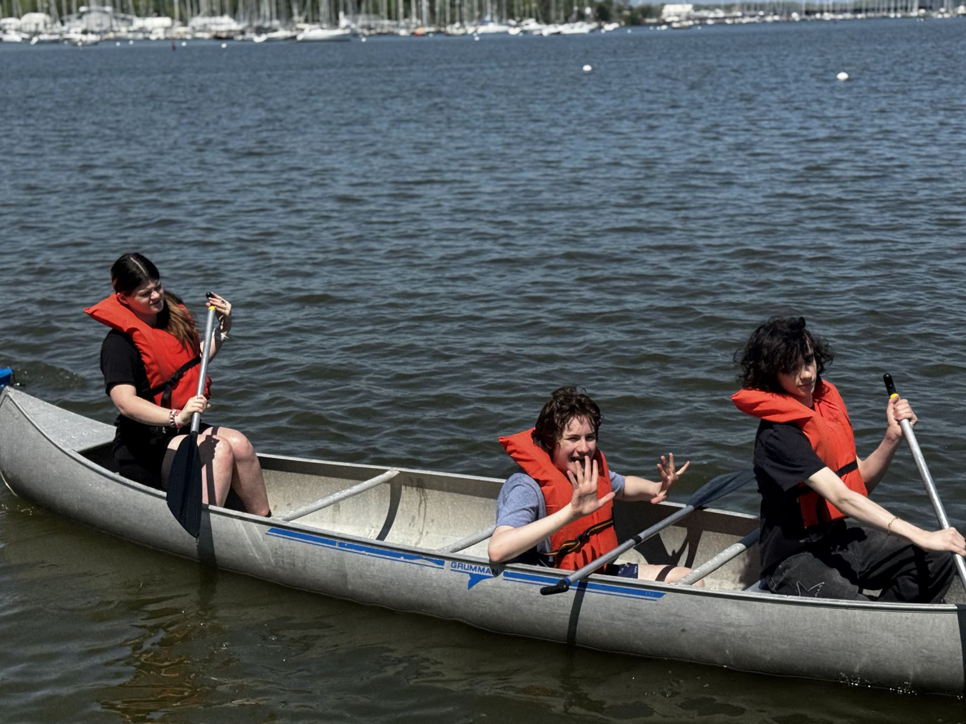 Three people in red life jackets paddling a canoe on a lake