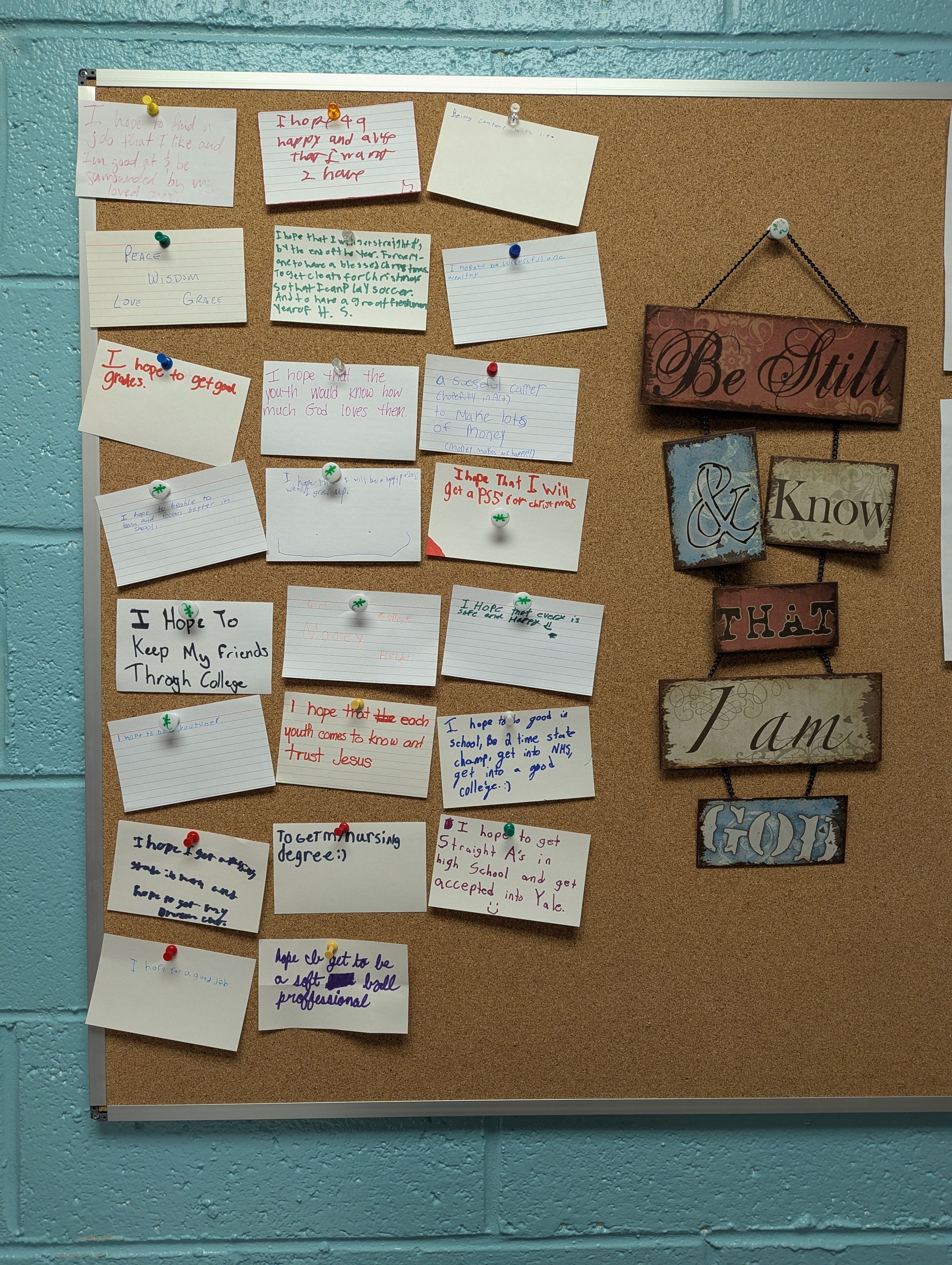 Corkboard with handwritten notes and a decorative sign reading