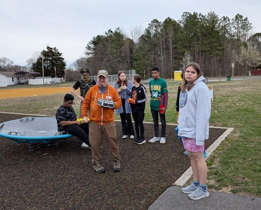 A group of children and an adult on a playground, some holding toys.