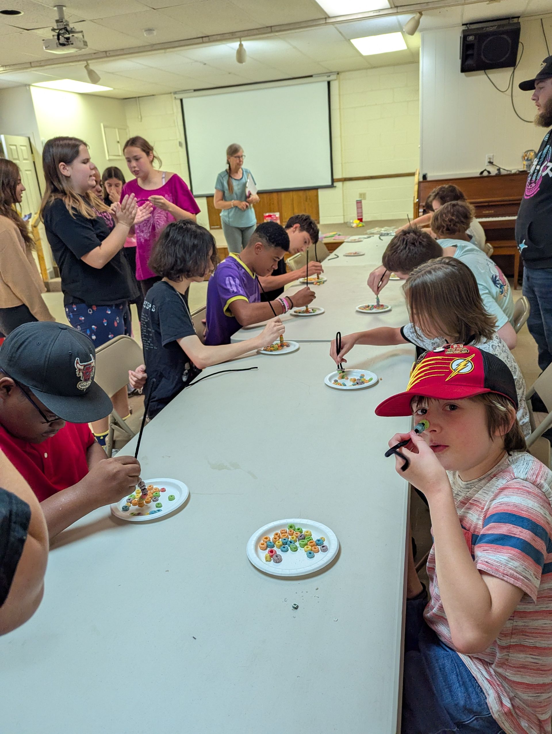 Youth at a table using forks, with others watching.
