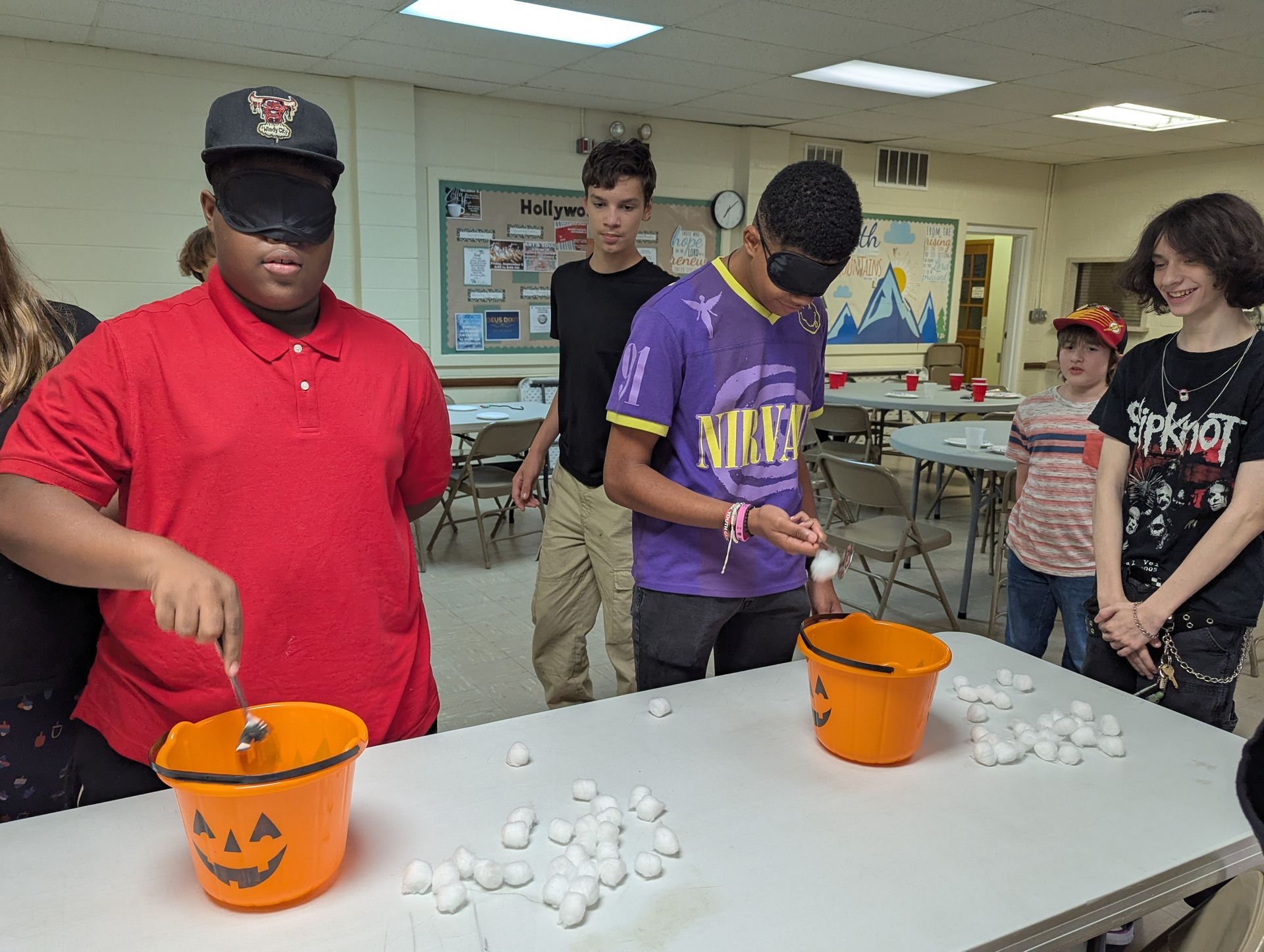 Youth playing a game, blindfolded, trying to put cotton balls into buckets.