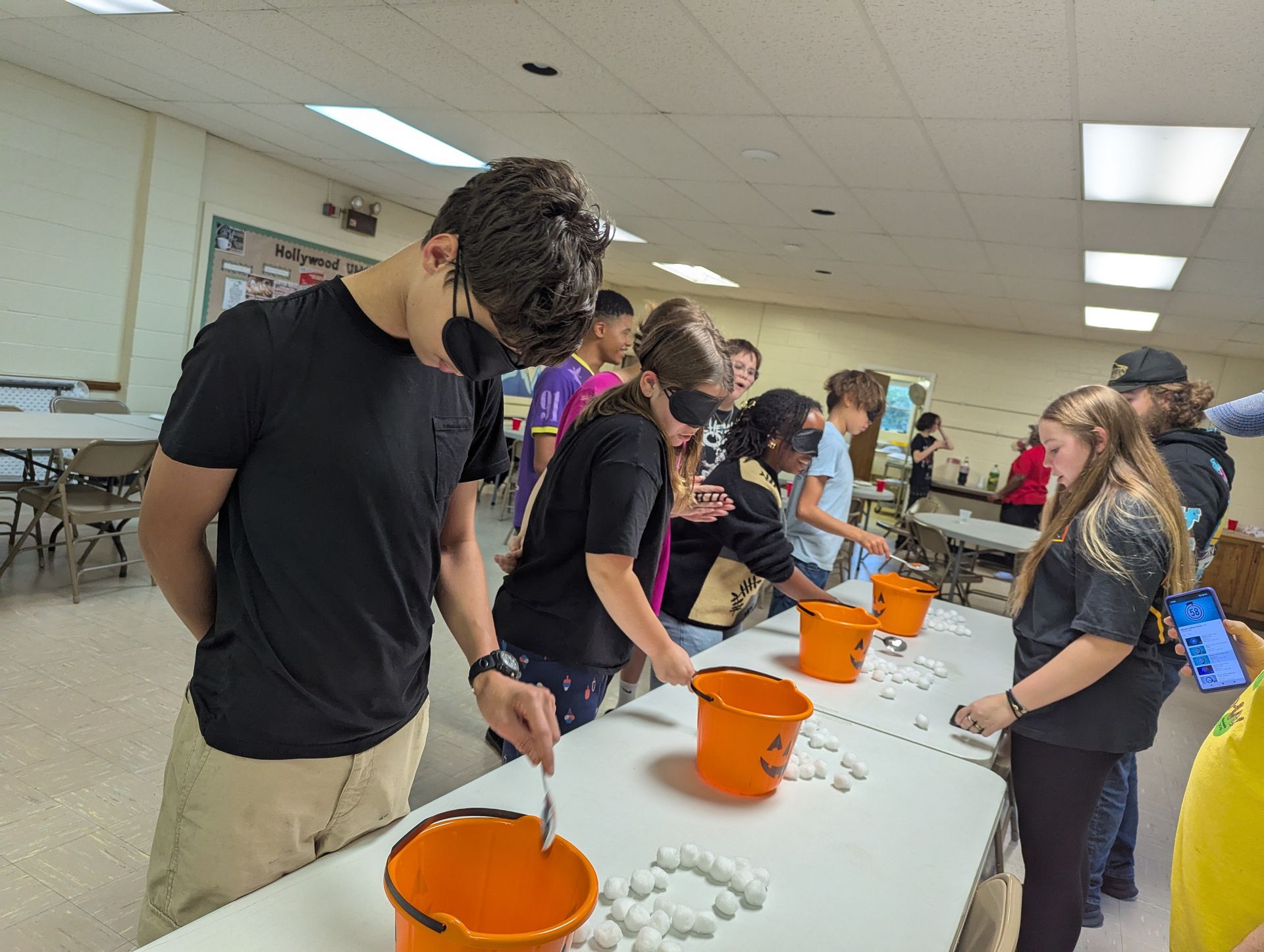 Youth playing a game with cotton balls and buckets. Indoor setting, group activity.
