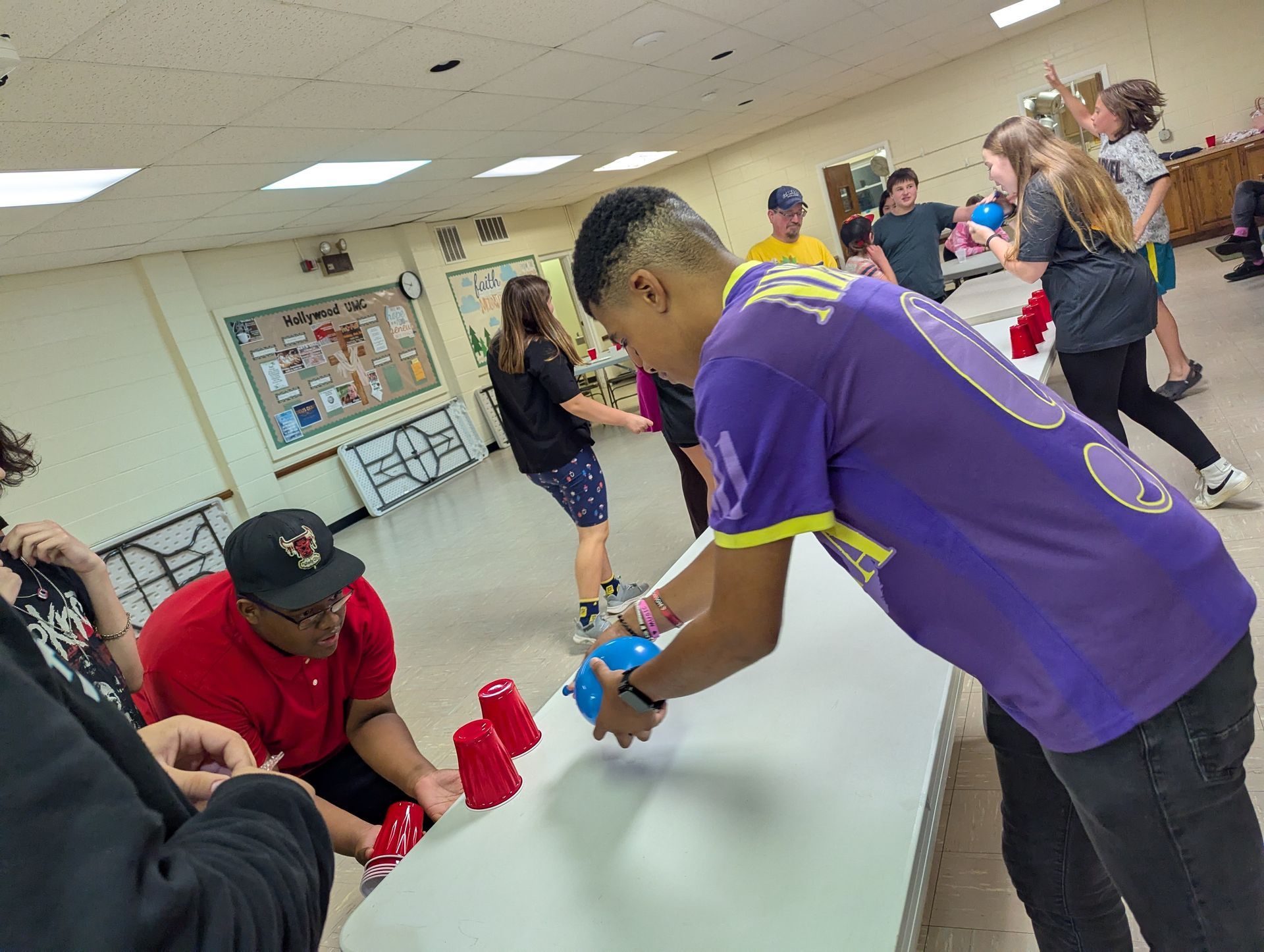 Youth playing a carnival game with cups on a table indoors.