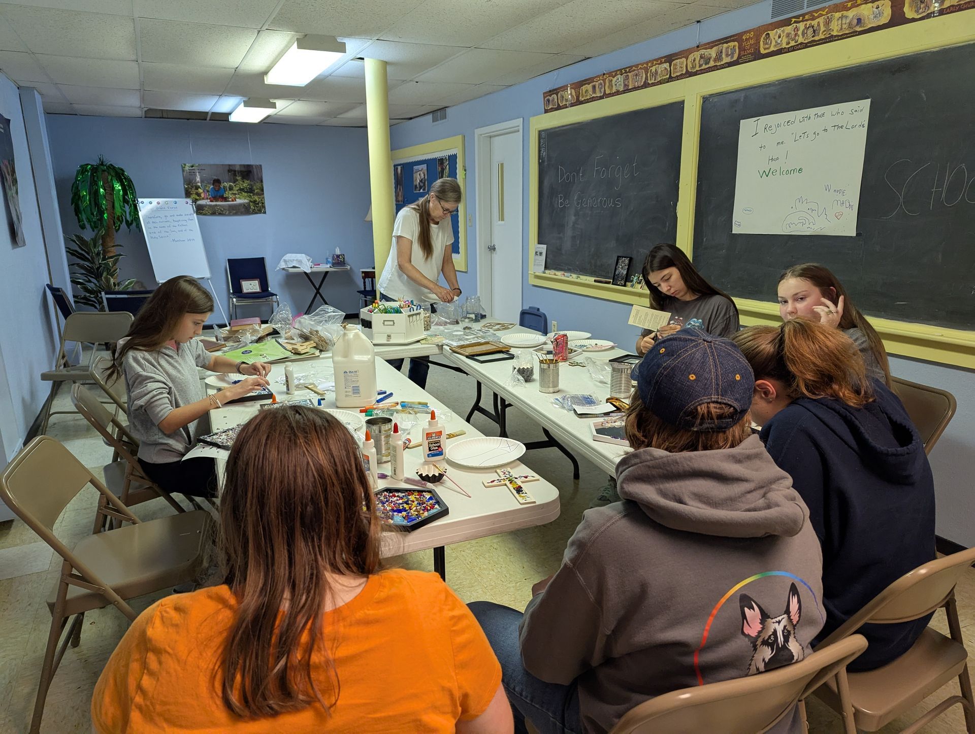 Youth at tables, crafting, in a classroom setting.