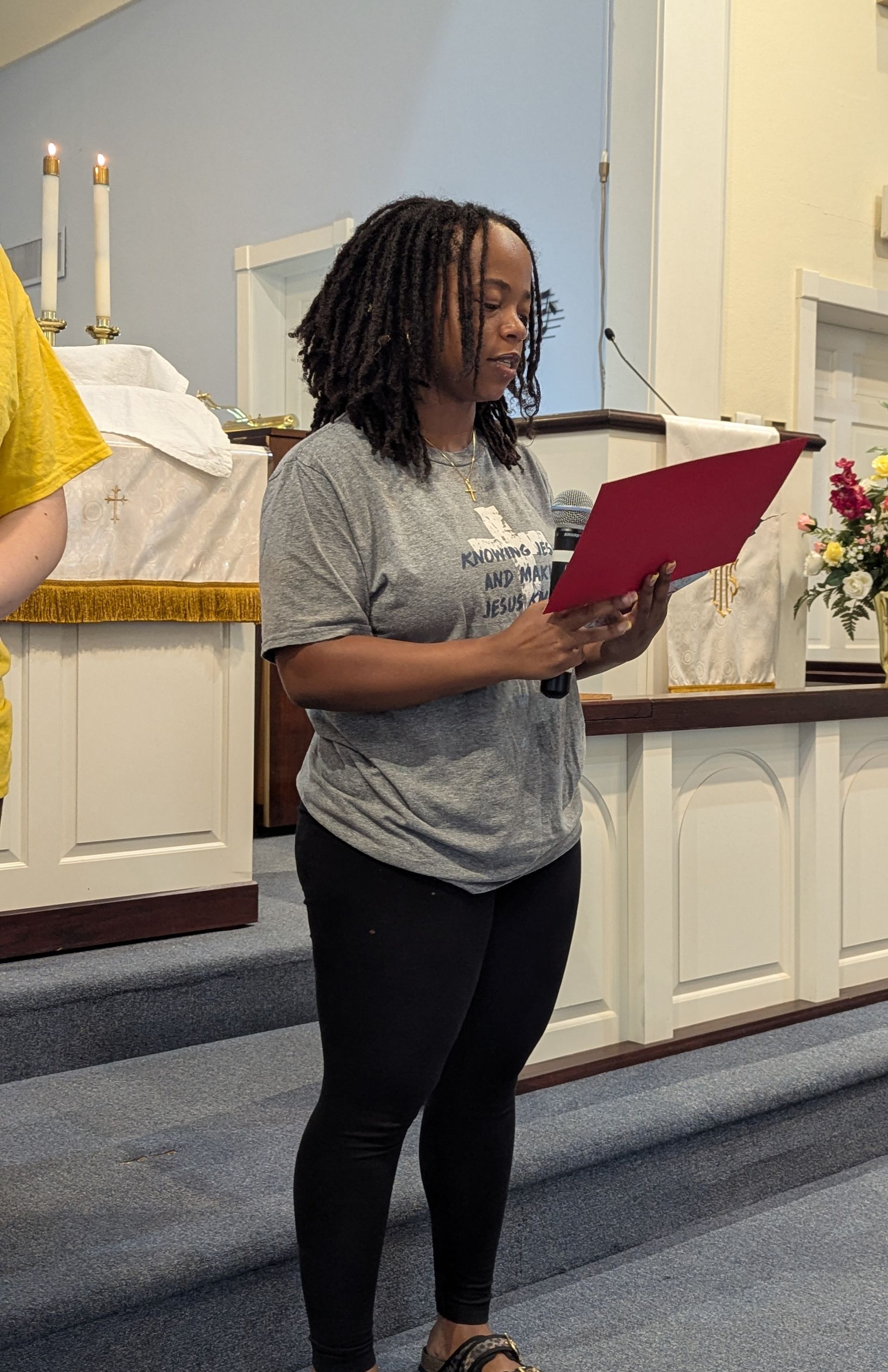 Youth reading from a red folder inside a church sanctuary near the altar