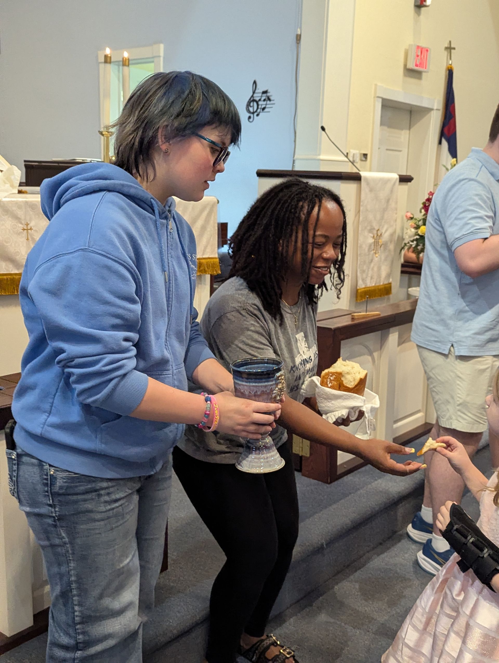 Youth giving communion in front of the church altar.