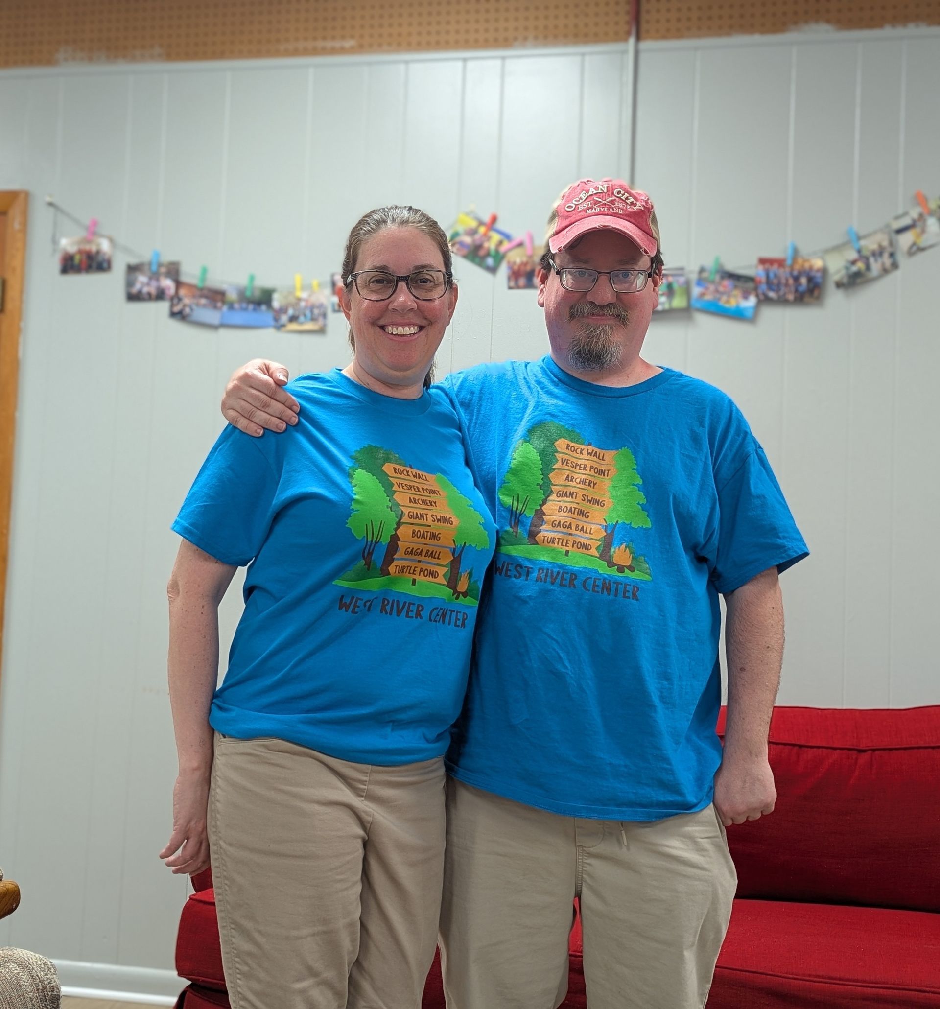 Our HUMC youth leaders in matching blue shirts and hats, smiling with arms around each other at an indoor event.