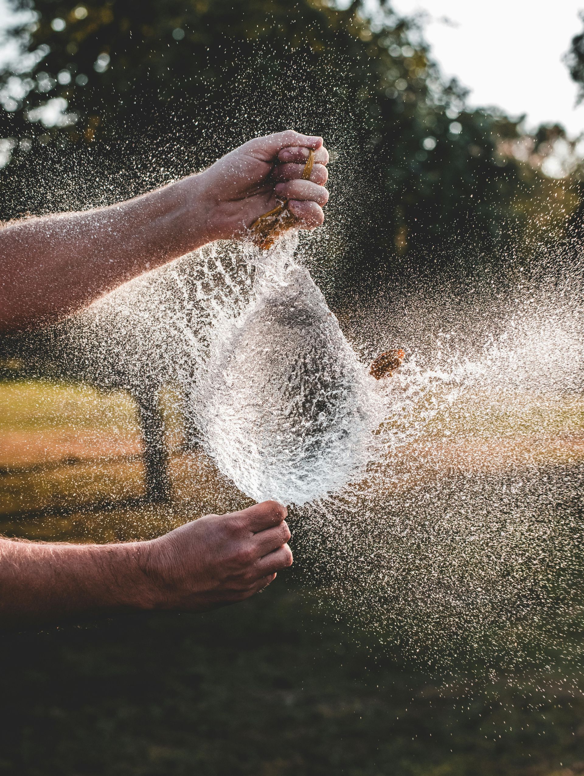 Hands sifting a spray of water outdoors at sunset