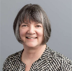 A woman wearing a black and white striped shirt smiles for the camera