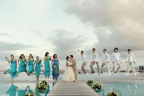 A bride and groom are posing for a picture with their wedding party on a dock.