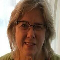 A close up of a woman wearing glasses and a green sweater.