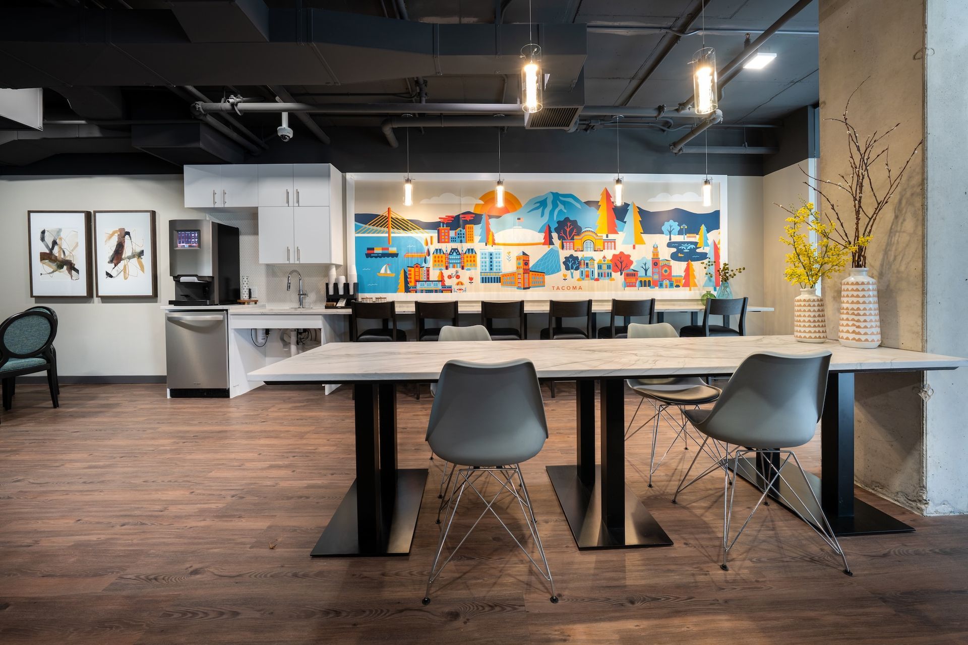 A large room with a table and chairs and a mural on the wall.