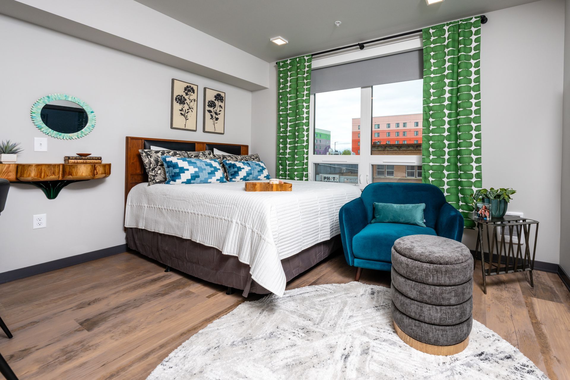 A bedroom with a bed , chair , ottoman and window.