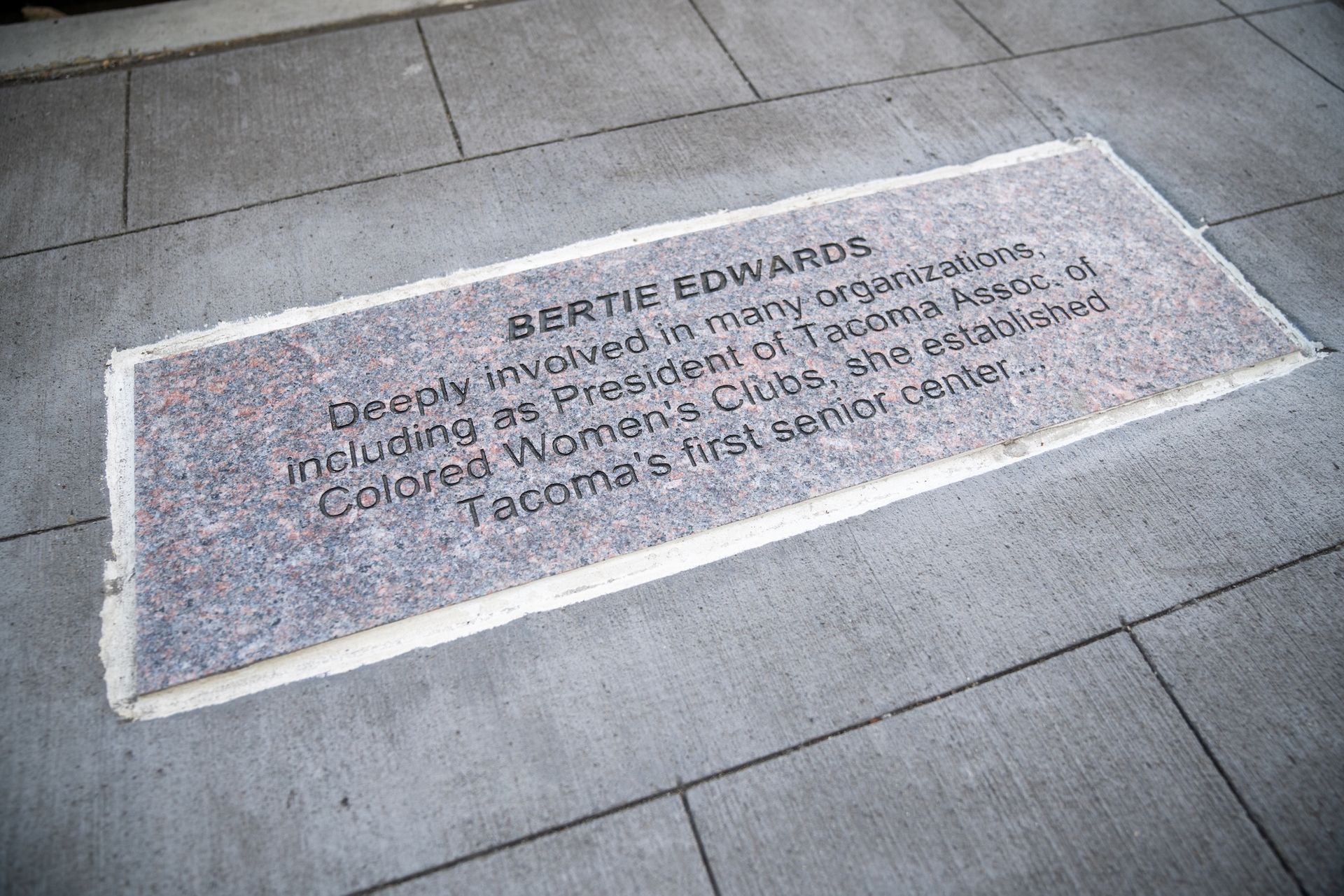 Stone plaque embedded in pavement, text reads
