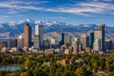 Denver skyline with high-rise buildings and snow-capped mountains under a clear blue sky