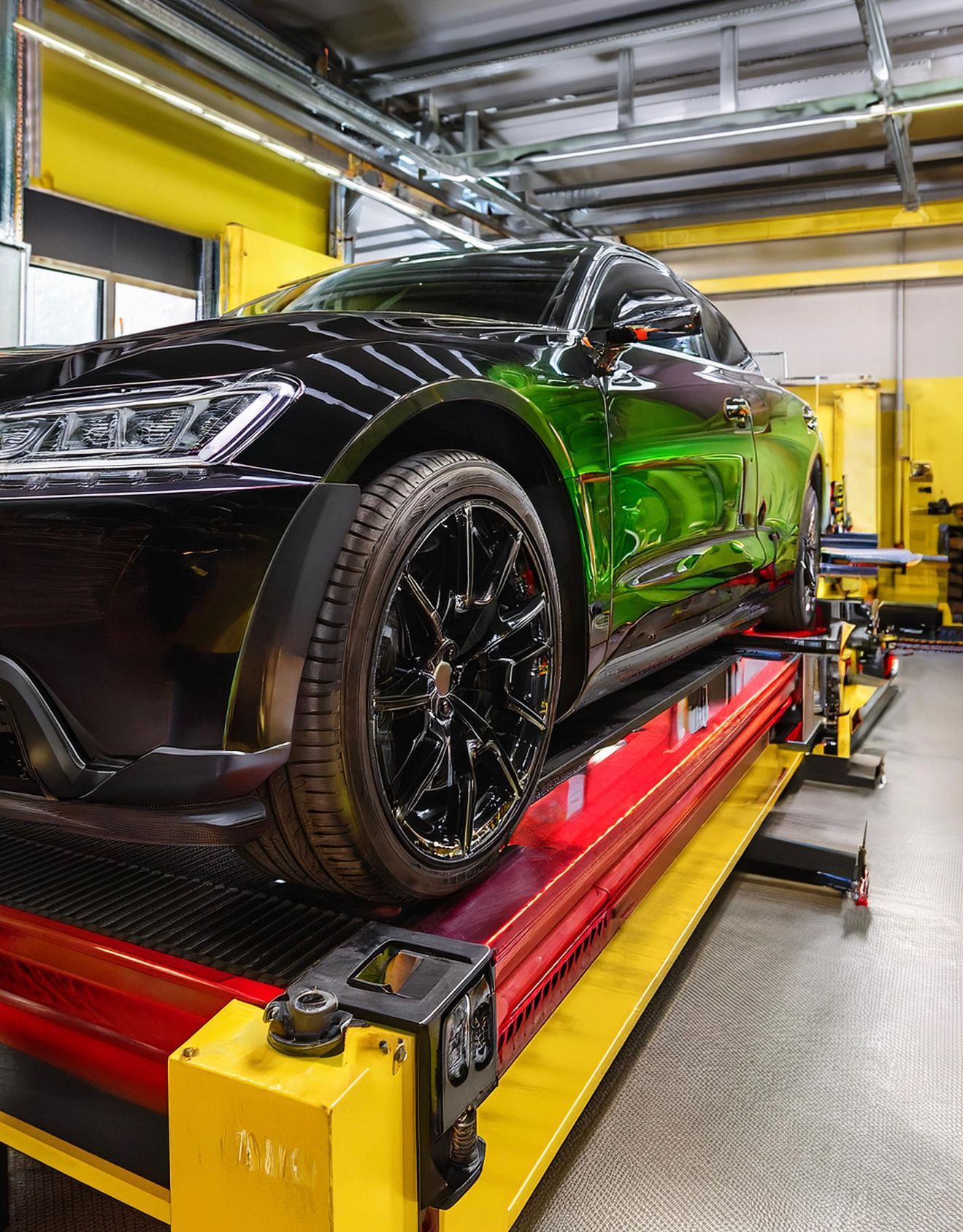 The image shows a BMW-like vehicle racked on our auto repair hoist in our Redwood City auto repair shop.  The vehicle is prepped for auto repair & service work.