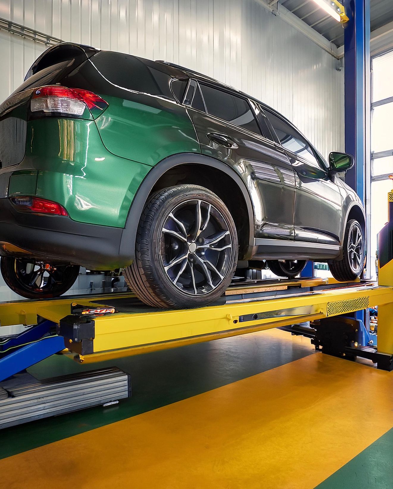 The image shows a Ford-like vehicle racked on our mechanics' hoist in preparation for auto repair & service at our Redwood City, CA facility.