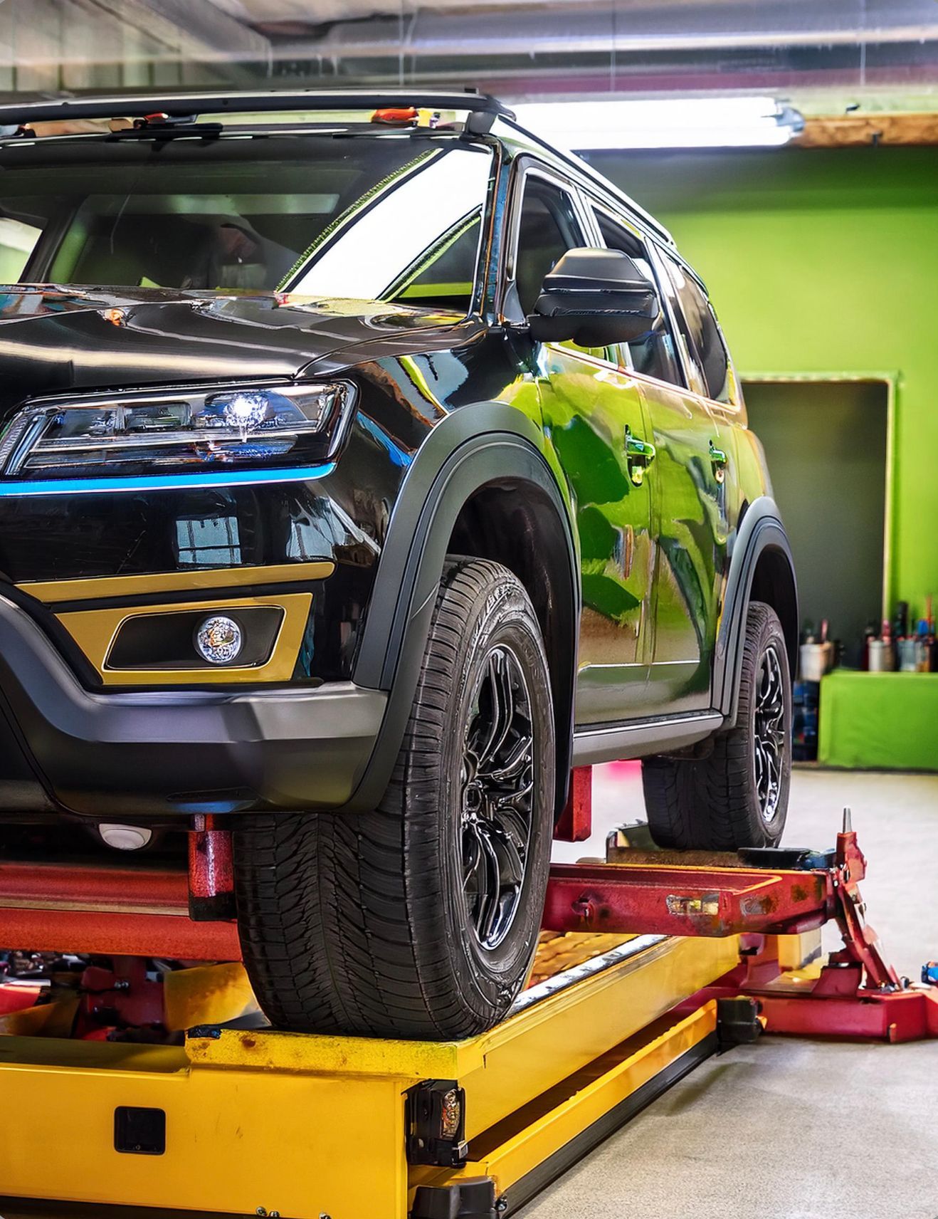 The image shows a Land Rover like vehicle racked on our mechanics hoist in preparation for auto repair and maintenance services at our facility in Redwood City, CA.