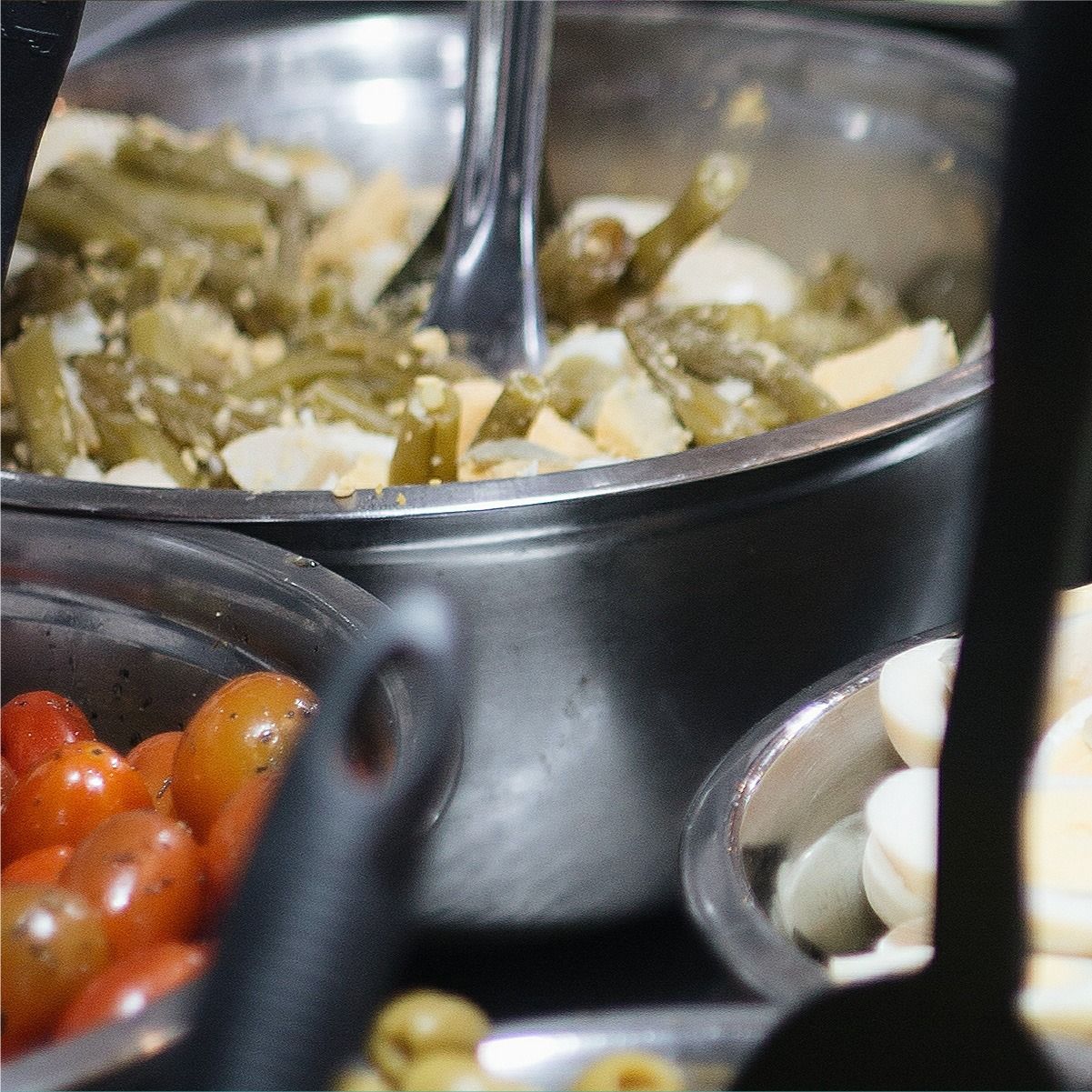 Barra de ensaladas con cuencos de tomates, judías verdes y huevos duros.