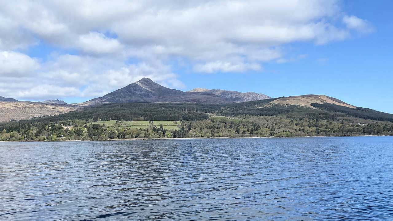 Arran reflected in a rippling water under a cloudy blue sky