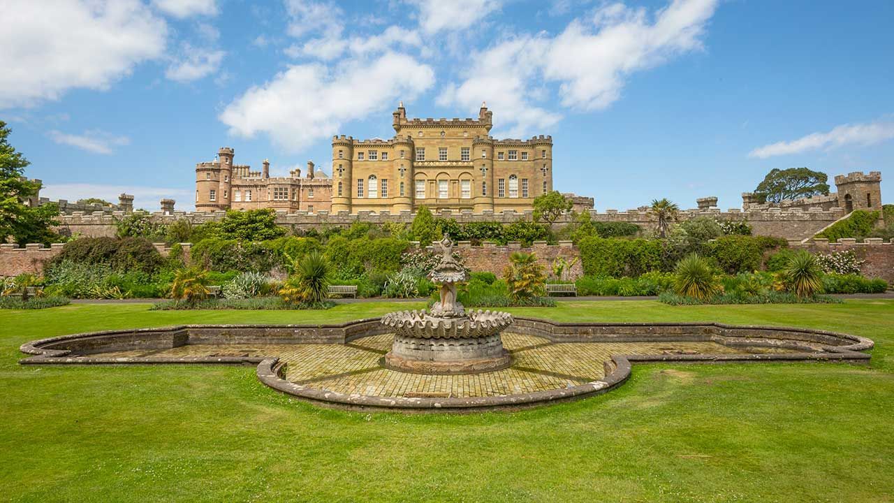 Grand historic Cuzlean with formal garden, fountain, and manicured lawn under a bright sky