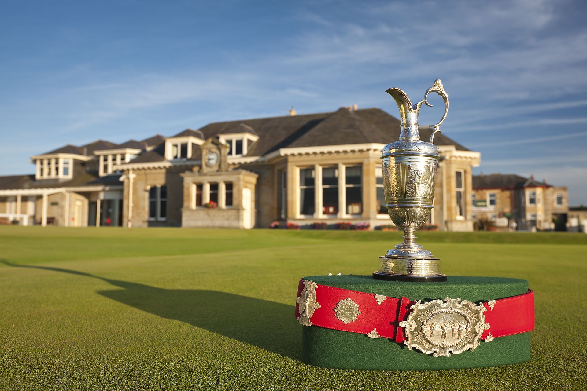 Golf trophy on red ribbon in front of a clubhouse and green fairway