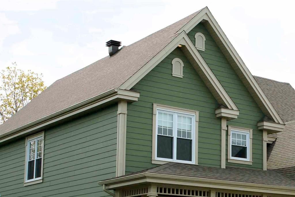 A green house with a brown roof and white windows