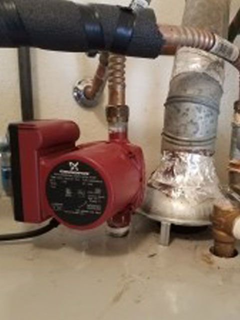 Red Grundfos circulation pump connected to copper pipes.