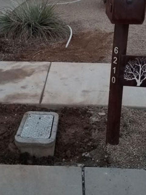 Concrete utility box near a sidewalk, mailbox post with address
