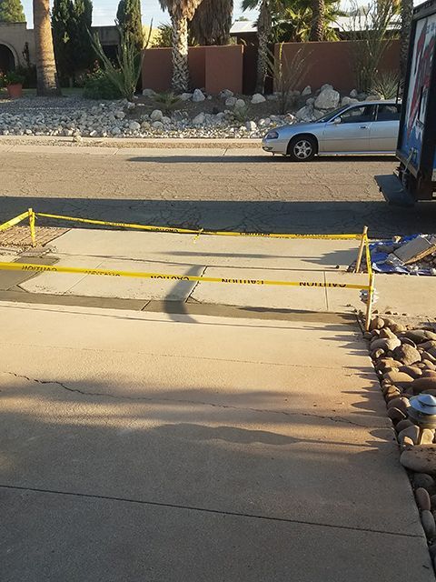 Driveway sectioned off with yellow caution tape; car in background.