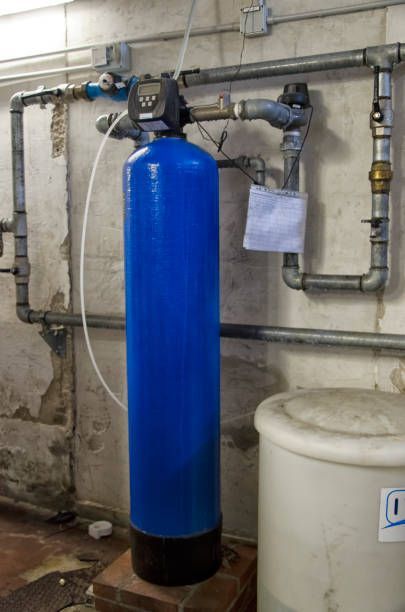 Blue water softener tank with connected plumbing in a basement.