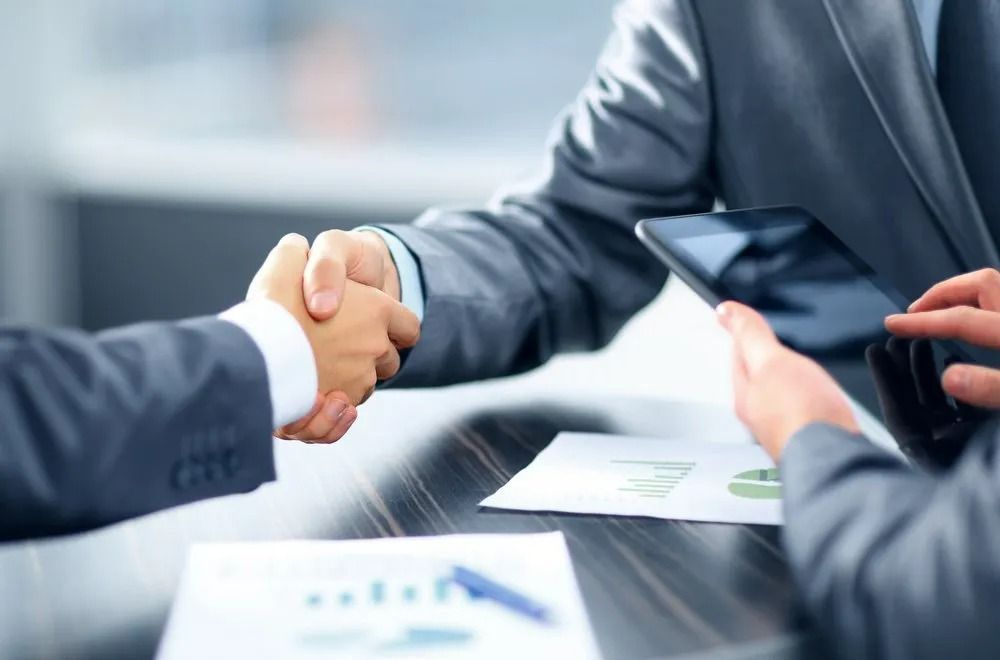 Two People in Suits Shaking Hands Over a Table — SSP Insurance In Rockhampton City, QLD