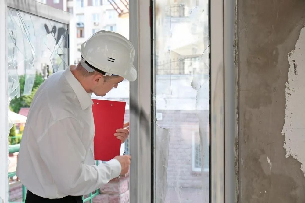 Construction Worker in Hard Hat Inspecting Broken Window — SSP Insurance In Mackay, QLD