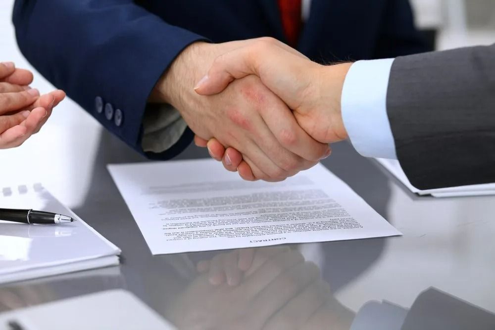 Two Men in Suits Shaking Hands Over a Contract on a Desk — SSP Insurance In Rockhampton City, QLD