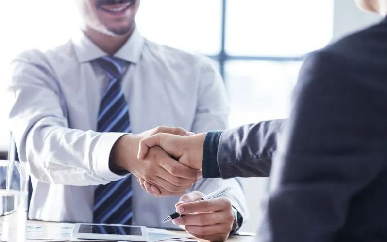 Two Men in Business Attire Shaking Hands, Smiling, Indoors — SSP Insurance In Rockhampton City, QLD