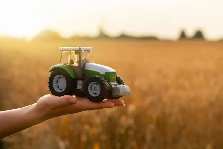 Hand Holding a Toy Green and White Tractor — SSP Insurance In Rockhampton City, QLD