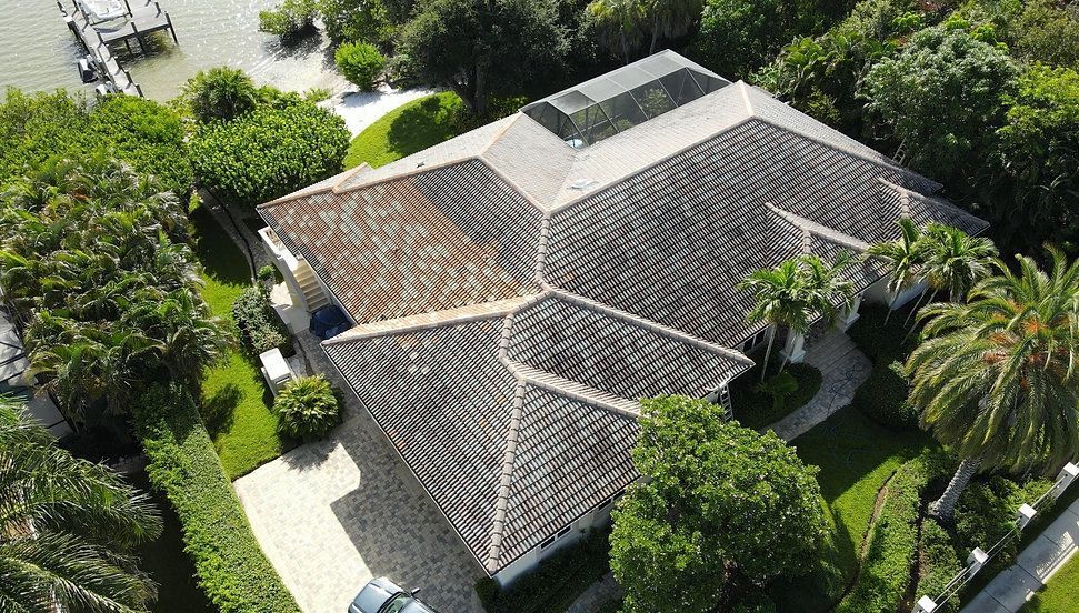 An aerial view of a house with a car parked in front of it surrounded by trees.