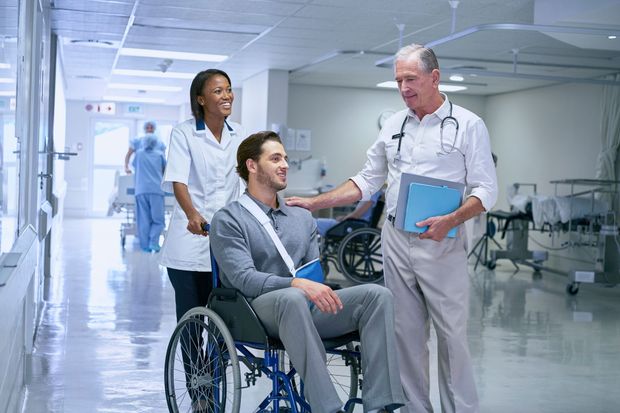 Doctor talking with a seated patient in a wheelchair in a bright hospital hallway