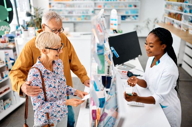 Pharmacy counter with a pharmacist helping two customers choose medication options
