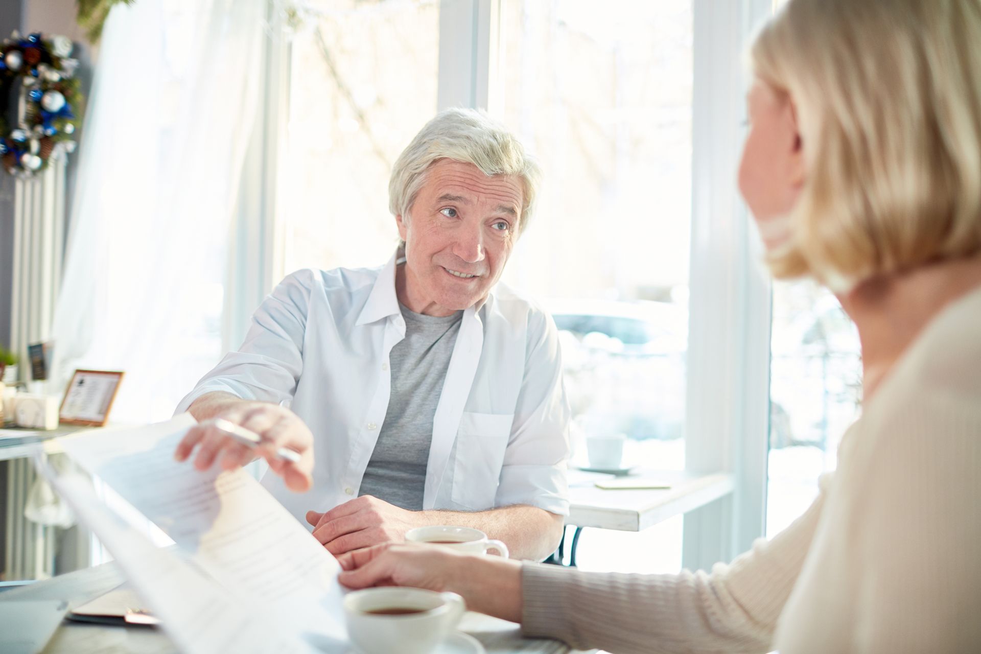 Two people in a bright office discussing documents across a desk