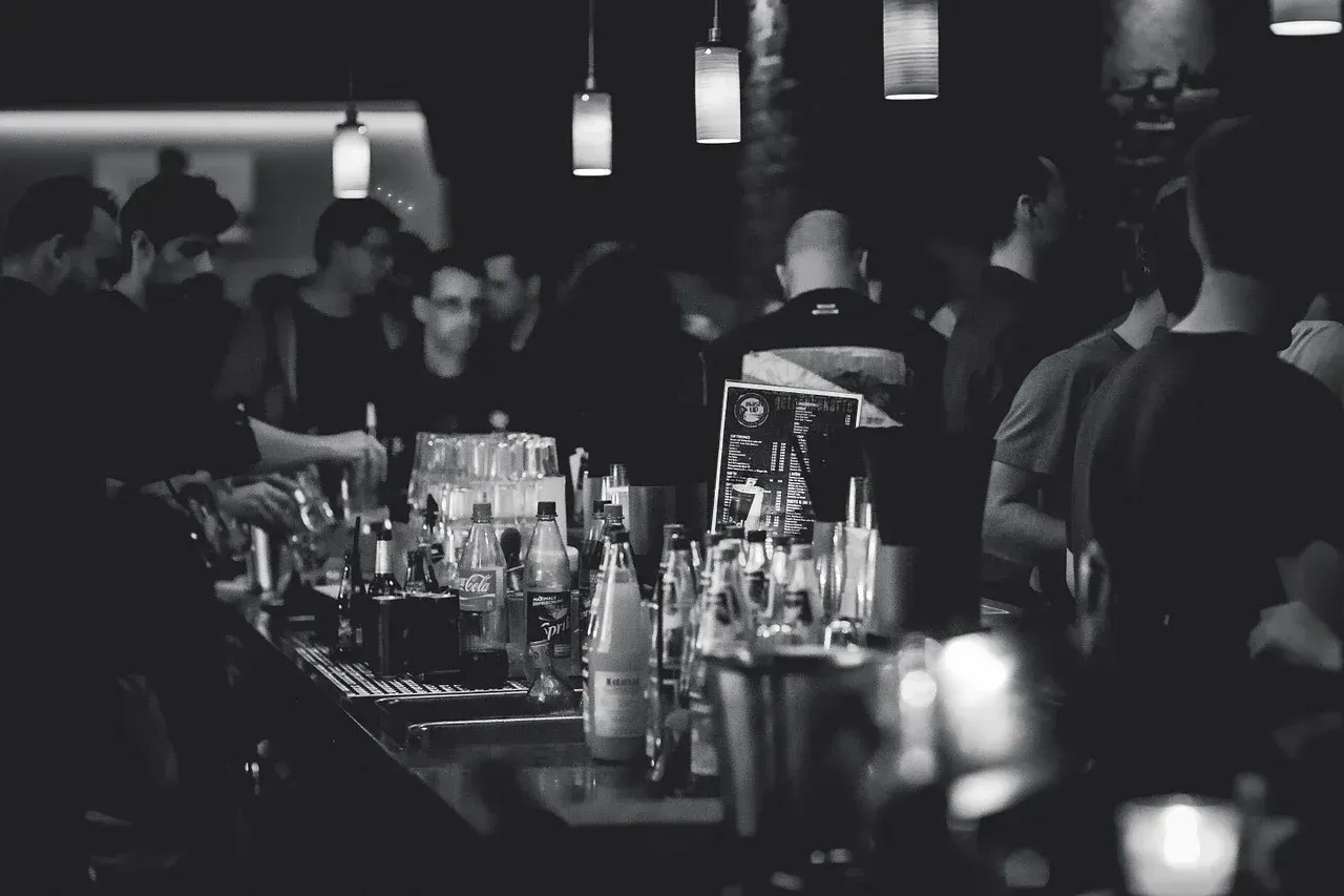 A black and white photo of a crowd of people at a bar.