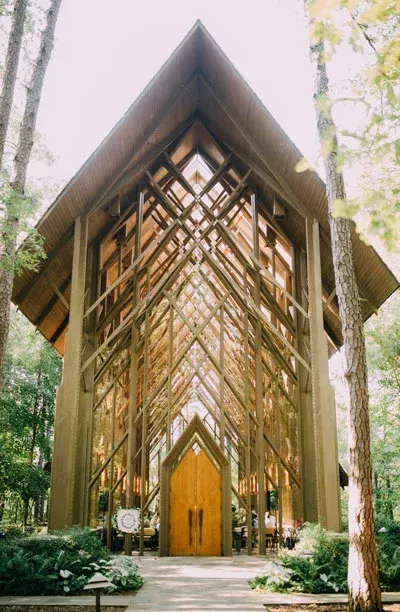 A church with a wooden roof and a wooden door in the middle of a forest.