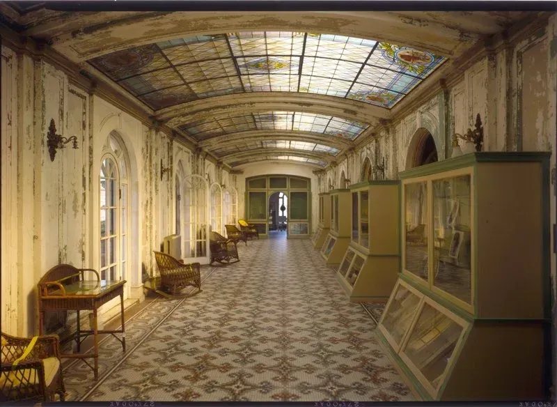 A long hallway with a stained glass ceiling and lots of furniture